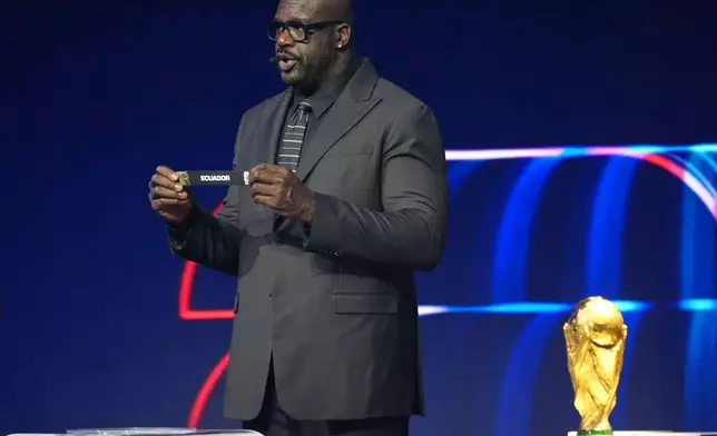 Former NBA player Shaquille O'Neal holds up the team name of Ecuador during the draw for the 2026 soccer World Cup at the Kennedy Center in Washington, Friday, Dec. 5, 2025. (AP Photo/Jacquelyn Martin)