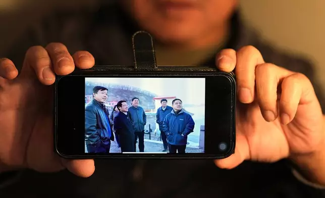 Former Chinese official Li Chuanliang shows one of the few pictures he has of himself, at right, from when he was vice mayor of Jixi, China, in the Mayflower Church community in Midland, Texas, Jan. 20, 2025. (AP Photo/Rebecca Blackwell)