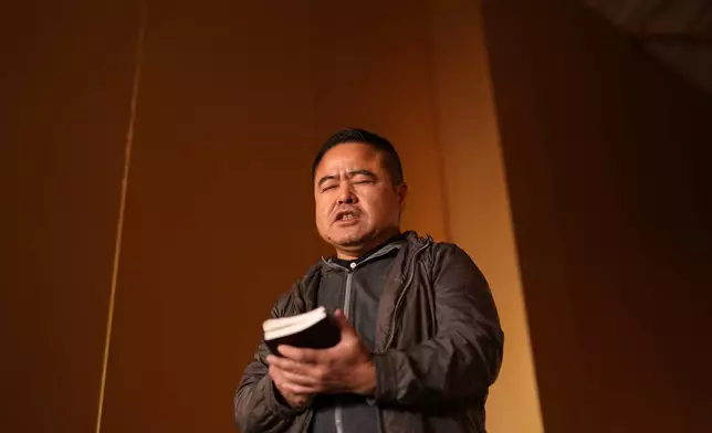 Former Chinese official Li Chuanliang holds a Bible as he prays inside the Mayflower Church temple sanctuary in Midland, Texas, Jan. 18, 2025. (AP Photo/Rebecca Blackwell)
