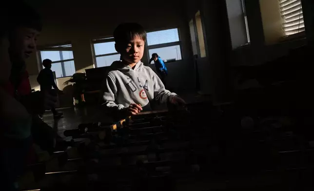 Nong Yitan plays foosball with other Mayflower Church kids inside the community hall in Midland, Texas, Jan. 18, 2025. (AP Photo/Rebecca Blackwell)
