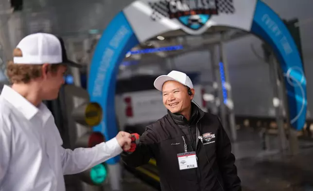 Mayflower Church Deacon Luo Changcheng, wearing a tag with the American name Peter, gets a fist bump from his boss, Eric Smith, as he works at a car wash in Midland, Texas, Jan. 20, 2025. (AP Photo/Rebecca Blackwell)