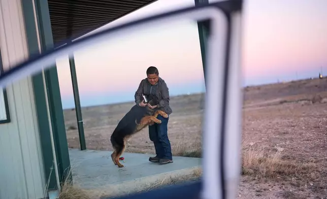 Former Chinese official Li Chuanliang greets his German shepherd, Hardy, as he returns from a trip to town from the Mayflower Church community in Midland, Texas, Jan. 18, 2025. (AP Photo/Rebecca Blackwell)