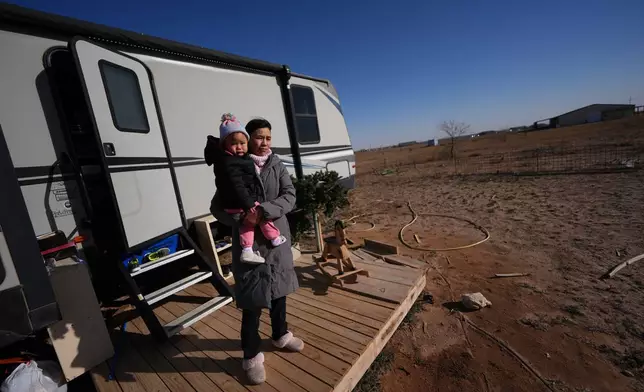 Mayflower Church member Chen Jingjing holds her daughter, Mo Nika, as she surveys the landscape from the porch of the family's trailer in Midland, Texas, Jan. 20, 2025. (AP Photo/Rebecca Blackwell)
