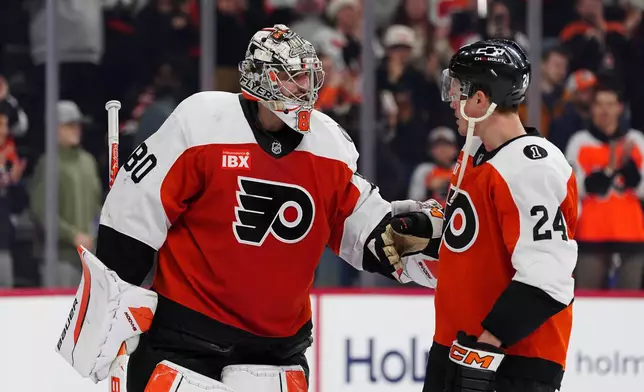 Philadelphia Flyers goaltender Dan Vladar, left, celebrates with Nick Seeler after a victory in an NHL hockey game against the Vancouver Canucks, Monday, Dec. 22, 2025, in Philadelphia. (AP Photo/Derik Hamilton)