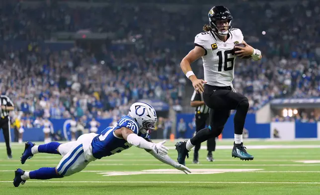 Jacksonville Jaguars quarterback Trevor Lawrence (16) scores past Indianapolis Colts safety Nick Cross (20) during the first half of an NFL football game Sunday, Dec. 28, 2025, in Indianapolis. (AP Photo/AJ Mast)