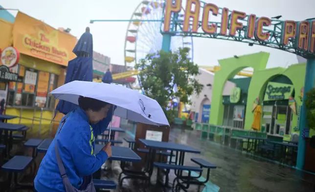 A tourist from China battles the rain on the Santa Monica pier Wednesday, Dec. 24, 2025, in Santa Monica, Calif. (AP Photo/Wally Skalij)