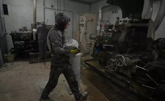 A craftsman carries a Common Green granite block to be machined into a curling stone at Kays Curling stone factory in Mauchline, Scotland, Tuesday, Nov. 11, 2025. (AP Photo/Alastair Grant)
