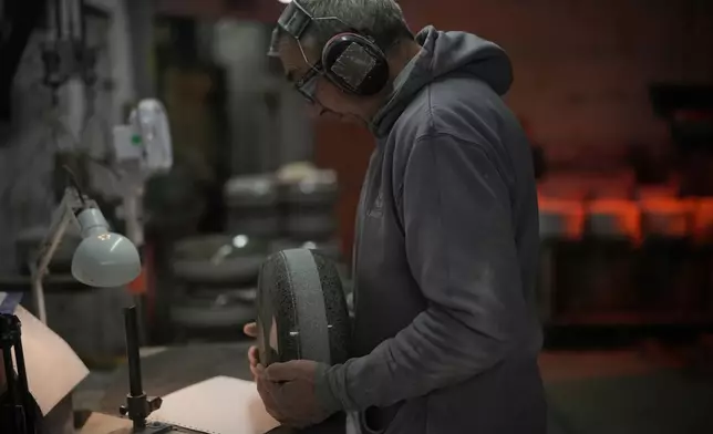 A craftsman checks a curling stone during a quality control phase at Kays Curling stone factory in Mauchline, Scotland, Tuesday, Nov. 11, 2025. (AP Photo/Alastair Grant,