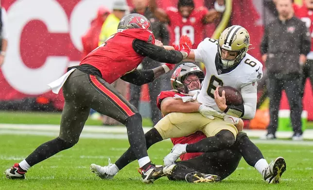 New Orleans Saints quarterback Tyler Shough (6) is sacked by Tampa Bay Buccaneers defensive tackle Greg Gaines and linebacker Haason Reddick, left, in the first half of an NFL football game, Sunday, Dec. 7, 2025, in Tampa, Fla. (AP Photo/Chris O'Meara)
