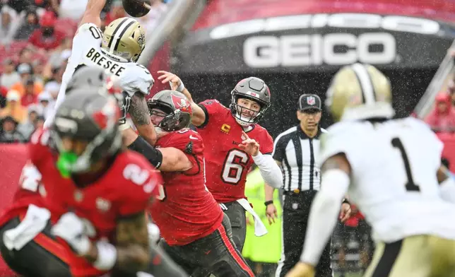 Tampa Bay Buccaneers quarterback Baker Mayfield (6) passes under pressure from New Orleans Saints defensive tackle Bryan Bresee (90) in the first half of an NFL football game, Sunday, Dec. 7, 2025, in Tampa, Fla. (AP Photo/Jason Behnken)
