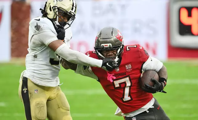 Tampa Bay Buccaneers running back Bucky Irving (7) carries against New Orleans Saints safety Jordan Howden (31) in the second half of an NFL football game, Sunday, Dec. 7, 2025, in Tampa, Fla. (AP Photo/Jason Behnken)