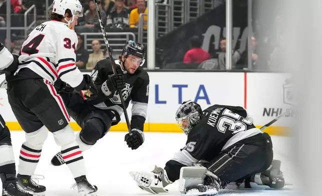 Los Angeles Kings goaltender Darcy Kuemper, right, makes a glove save as Chicago Blackhawks center Colton Dach, left, watches and right wing Alex Laferrierek trips during the first period of an NHL hockey game Thursday, Dec. 4, 2025, in Los Angeles. (AP Photo/Mark J. Terrill)