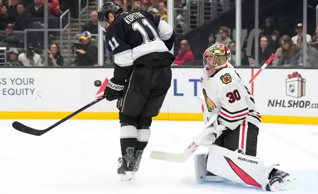 Los Angeles Kings center Anze Kopitar, left, tries to tip a shot past Chicago Blackhawks goaltender Spencer Knight during the second period of an NHL hockey game Thursday, Dec. 4, 2025, in Los Angeles. (AP Photo/Mark J. Terrill)
