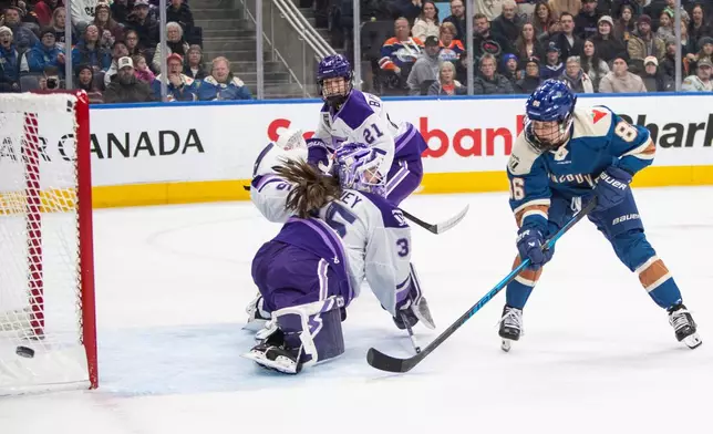 CORRECTS TO PWHL IN EDMONTON, SATURDAY NOT IIHF IN MINNEAPOLIS, FRIDAY - Minnesota Frost goalie Maddie Rooney (35) makes a save against Vancouver Goldeneyes' Michela Cava (86) as Frost's Mae Batherson (21) looks on during second-period PWHL hockey game action in Edmonton, Alberta, Saturday, Dec. 27, 2025. (Amber Bracken/The Canadian Press via AP)