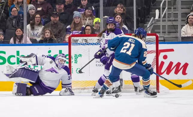 Minnesota Frost goalie Maddie Rooney (35) looks for the puck with teammate Natalie Buchbinder (22) and Vancouver Goldeneyes' Ashton Bell (21) during first-period PWHL hockey game action in Edmonton, Alberta, Saturday, Dec. 27, 2025. (Amber Bracken/The Canadian Press via AP)
