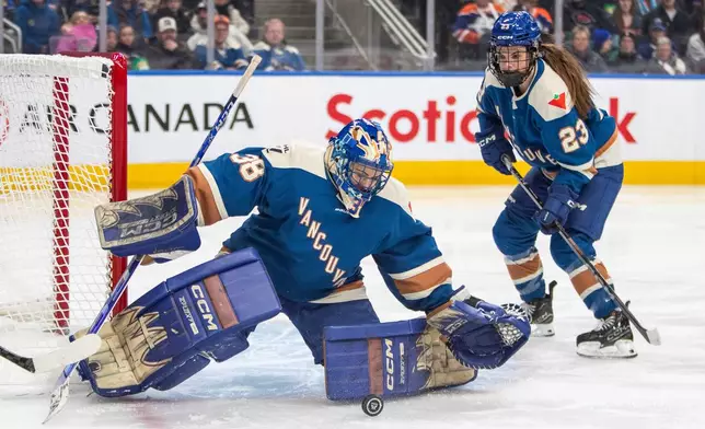 Vancouver Goldeneyes goalie Emerance Maschmeyer (38) keeps out a Minnesota Frost puck as Mellissa Channell-Watkins (23) looks on during the first period of an PWHL game in Edmonton, Saturday, Dec. 27, 2025. (Amber Bracken/The Canadian Press via AP)