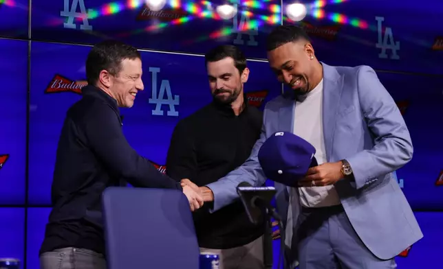 Edwin Díaz, right, shakes hands with President of Baseball Operations Andrew Friedman, left, while standing next to General Manager Brandon Gomes during his introduction as a new member of the Los Angeles Dodgers baseball team Friday, Dec. 12, 2025, in Los Angeles. (AP Photo/Ethan Swope)