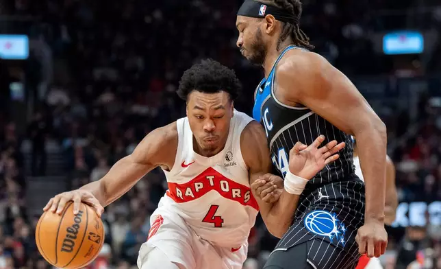Toronto Raptors forward Scottie Barnes (4) drives against Orlando Magic center Wendell Carter Jr., right, during first-half NBA basketball game action in Toronto, Monday Dec. 29, 2025. (Frank Gunn/The Canadian Press via AP)