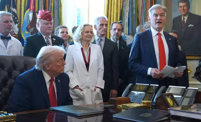 President Donald Trump listens as Centers for Medicare &amp; Medicaid Services administrator Dr. Mehmet Oz speaks during an executive order signing in the Oval Office of the White House, Thursday, Dec. 18, 2025, in Washington. (AP Photo/Evan Vucci)