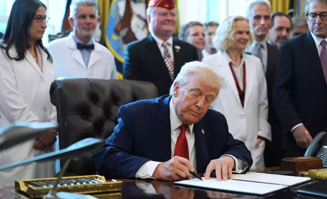 President Donald Trump signs an executive order reclassifying marijuana as a less dangerous drug in the Oval Office of the White House, Thursday, Dec. 18, 2025, in Washington. (AP Photo/Evan Vucci)