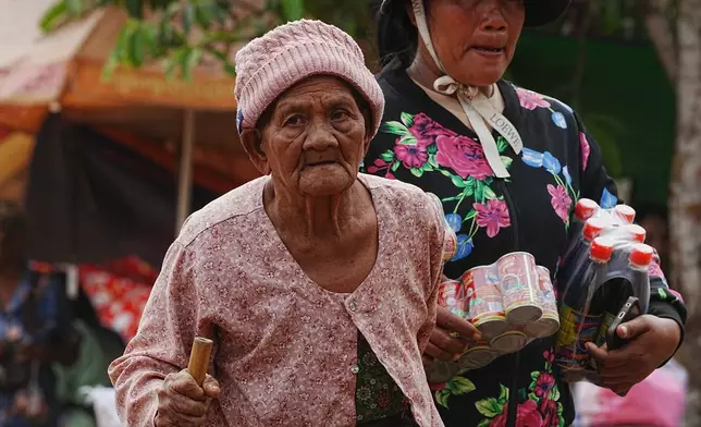 A woman, left, walks as she takes refuge at Batthkoa primary school in Oddar Meanchey province, Cambodia Wednesday, Dec. 10, 2025, after fleeing from home following a fighting between Thailand and Cambodia over territorial claims. (AP Photo/Heng Sinith)