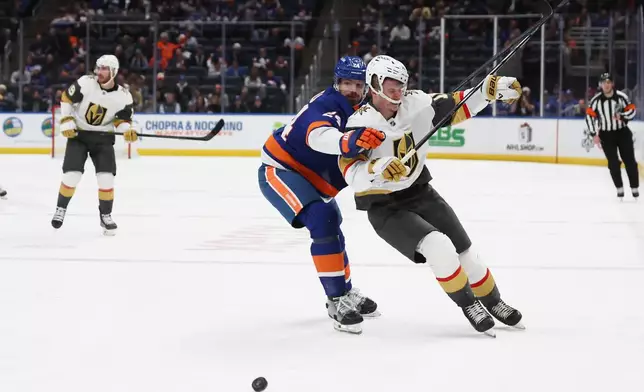 New York Islanders' Scott Mayfield (24) and Vegas Golden Knights' Pavel Dorofeyev collide while going after the puck during the third period of an NHL hockey game, Tuesday, Dec. 9, 2025, in Elmont, N.Y. (AP Photo/Heather Khalifa)