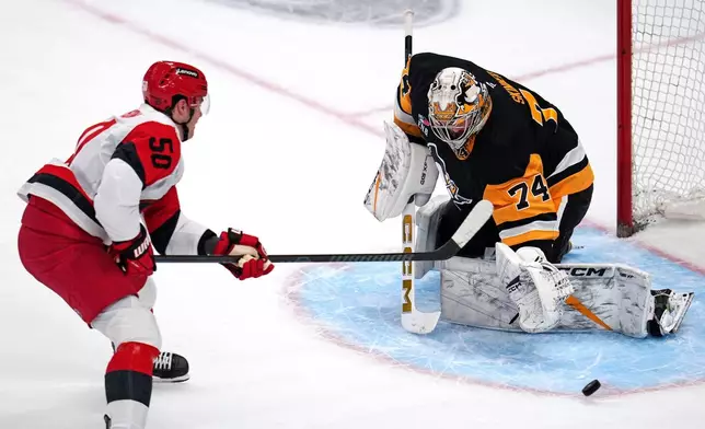 Pittsburgh Penguins goaltender Stuart Skinner (74) blocks a shot by Carolina Hurricanes' Eric Robinson during the first period of an NHL hockey game in Pittsburgh, Tuesday, Dec. 30, 2025. (AP Photo/Gene J. Puskar)