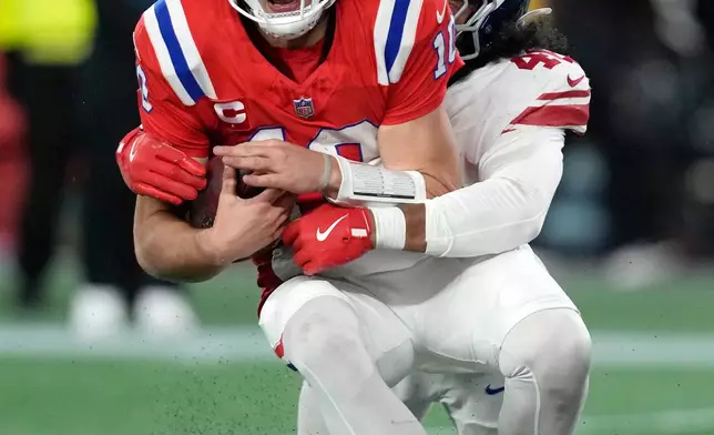 New England Patriots quarterback Drake Maye, front, is sacked by New York Giants linebacker Zaire Barnes, back, during the second half of an NFL football game Monday, Dec. 1, 2025, in Foxborough, Mass. (AP Photo/Charles Krupa)