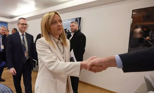 Italy's Prime Minister Giorgia Meloni, center, is greeted as she arrives for a round table meeting on migration at the EU Summit in Brussels, Thursday, Dec. 18, 2025. (AP Photo/Olivier Hoslet, Pool Photo via AP)