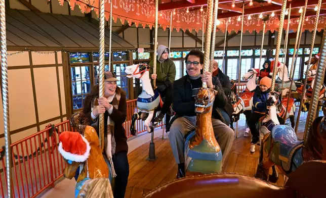 Christina and Raul Nieves of Windsor Locks ride the Bushnell Park Carousel in Hartford, Conn., Friday, Dec. 5, 2025. Scenes from the Hallmark movie "Ghost of Christmas Always" were filmed at the carousel. (AP Photo/Jessica Hill)