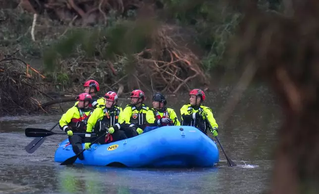 FILE - Officials ride a boat as they arrive to assist with a recovery effort at Camp Mystic along the Guadalupe River, July 6, 2025, in Hunt, Texas, after a flash flood swept through the area. (AP Photo/Julio Cortez, File