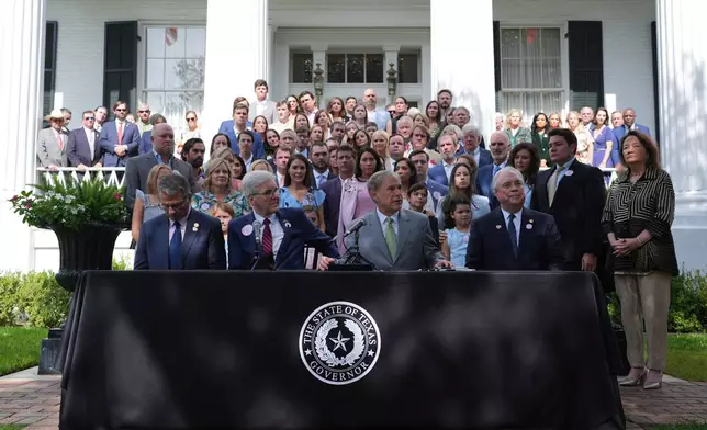 FILE - Parents and family of children who died at Camp Mystic join Texas Gov. Greg Abbott, second from right, as he signs camp safety bills, Sept. 5, 2025, in Austin, Texas. (AP Photo/Eric Gay, File