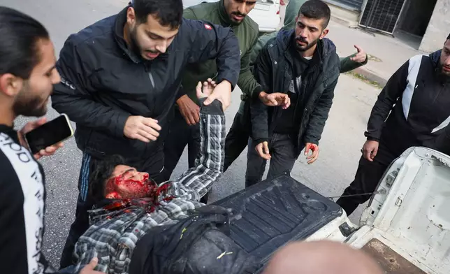 A man seriously injured by a thrown stone is taken away from the area after clashes erupted between Alawite protesters from the Alawite religious minority and counterprotesters, two days after a bomb in an Alawite mosque in Homs killed eight people and wounded 18 during Friday prayers, in Latakia, Syria's coastal region, Sunday, Dec. 28, 2025. (AP Photo/Omar Albam)
