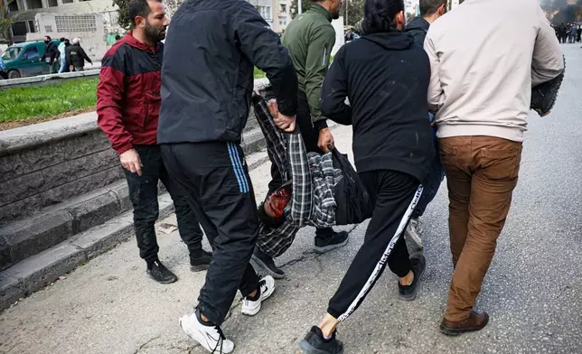 A man seriously injured by a thrown stone is taken away from the area after clashes erupted between Alawite protesters from the Alawite religious minority and counterprotesters, two days after a bomb in an Alawite mosque in Homs killed eight people and wounded 18 during Friday prayers, in Latakia, Syria's coastal region, Sunday, Dec. 28, 2025. (AP Photo/Omar Albam)