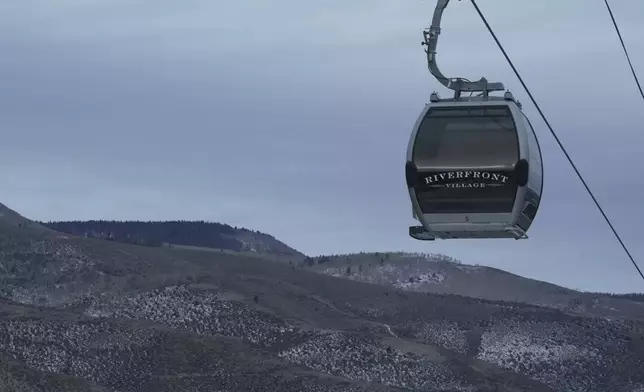 A gondola hangs in front of snow-scarce mountains Thursday, Dec. 18, 2025, in Avon, Colo. (AP Photo/Brittany Peterson)
