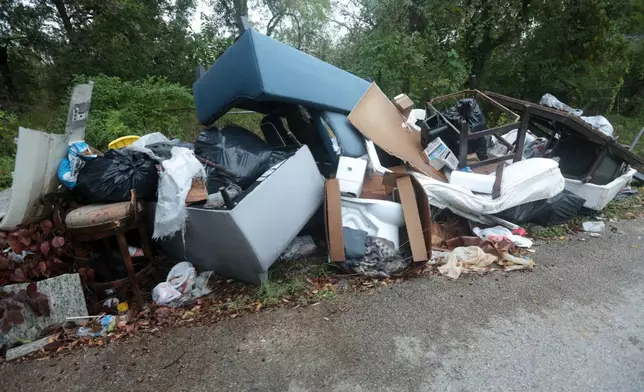 A toilet lays among large piles of trash and debris littered on a narrow roadway in the TrinityGardens neighborhood in northwest Houston, Thursday, Dec. 4, 2025, Thursday, Dec. 4, 2025. (AP Photo/Lekan Oyekanmi )