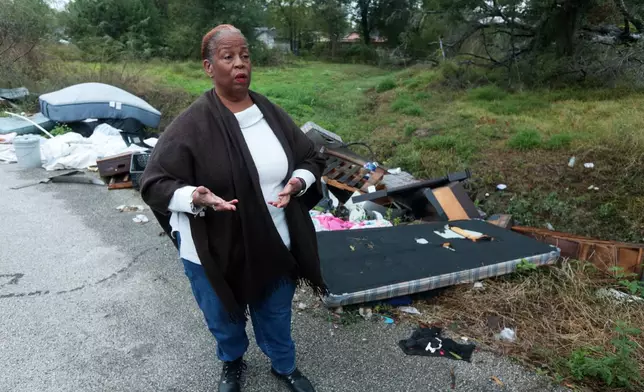Huey German-Wilson, Trinity-Houston Community President, is interviewed near large piles of trash and debris littering a narrow roadway in the Trinity Gardens neighborhood in northwest Houston, Thursday, Dec. 4, 2025. (AP Photo/Lekan Oyekanmi )