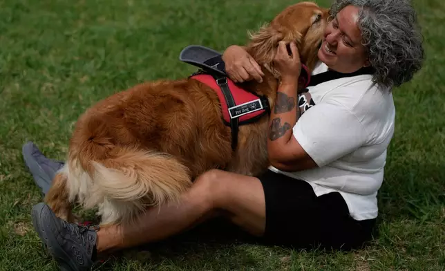 A woman hugs her dog at a Palermo neighborhood park as people try to set a world record of most Golden Retrievers gathered in a park, in Buenos Aires, Argentina, Monday, Dec. 8, 2025. (AP Photo/Natacha Pisarenko)