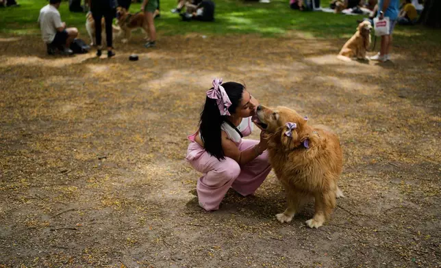 Cintia Gabriela kisses her pet Mora in a Palermo neighborhood park as dog owners try to set a world record of most Golden Retrievers gathered in a park, in Buenos Aires, Argentina, Monday, Dec. 8, 2025. (AP Photo/Natacha Pisarenko)