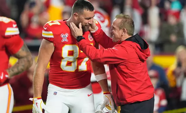 Kansas City Chiefs tight end Travis Kelce, left, talks with defensive coordinator Steve Spagnuolo prior to an NFL football game against the Denver Broncos Thursday, Dec. 25, 2025, in Kansas City, Mo. (AP Photo/Charlie Riedel)