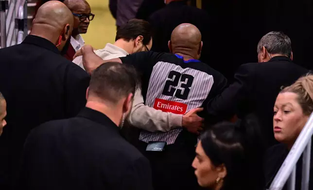 Referee Tre Maddox, center, is assisted by members of the training staff after sustaining an injury running off the floor in the first half of an NBA basketball game between the Cleveland Cavaliers and Chicago Bulls, Friday, Dec. 19, 2025, in Cleveland. (AP Photo/David Dermer)