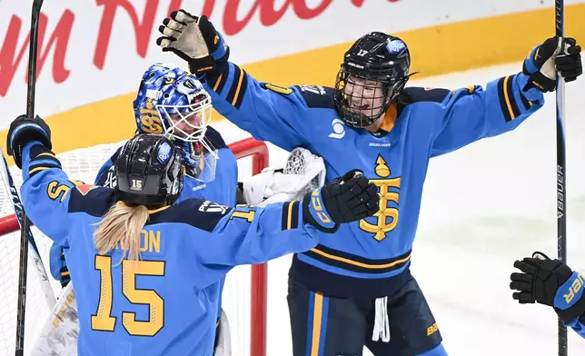 Toronto Sceptres goaltender Elaine Chuli, center, celebrates with teammates Savannah Harmon (15) and Ella Shelton, right, after defeating the Montreal Victoire in a PWHL hockey game in Montreal, Saturday, Dec. 27, 2025. (Graham Hughes/The Canadian Press via AP)