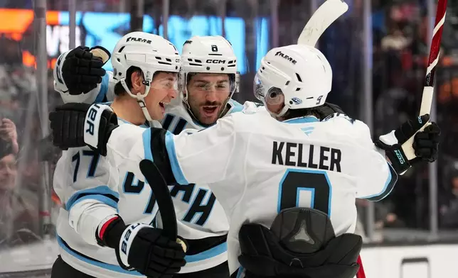 Utah Mammoth right wing JJ Peterka left, celebrates his goal with center Nick Schmaltz, center, and right wing Clayton Keller during the second period of an NHL hockey game against the Anaheim Ducks, Wednesday, Dec. 3, 2025, in Anaheim, Calif. (AP Photo/Mark J. Terrill)