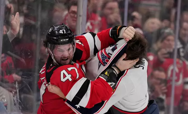 New Jersey Devils' Paul Cotter, left, fights with Columbus Blue Jackets' Brendan Smith during the second period of an NHL hockey game in Newark, N.J., Monday, Dec. 1, 2025. (AP Photo/Seth Wenig)