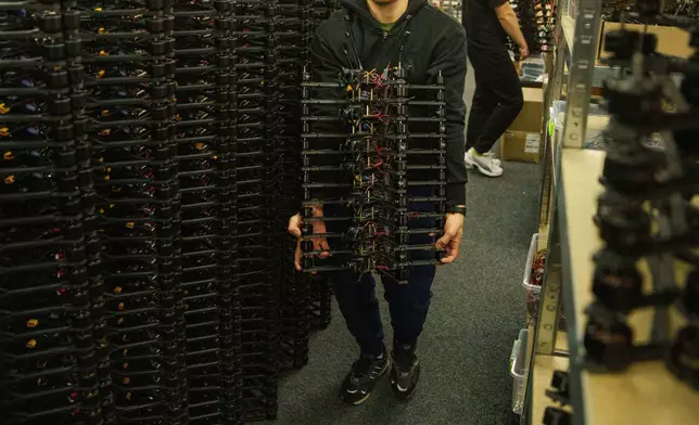An engineer carries FPV drones of "General Cherry" company at the workshop in Ukraine, on Dec. 4, 2025. (AP Photo/Evgeniy Maloletka)