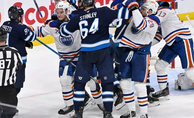 Winnipeg Jets' Logan Stanley (64) grabs Edmonton Oilers' Vasily Podkolzin (92) and Leon Draisaitl (29) after a whistle during the third period of an NHL game in Winnipeg, Monday Dec. 29, 2025. (Fred Greenslade/The Canadian Press via AP)