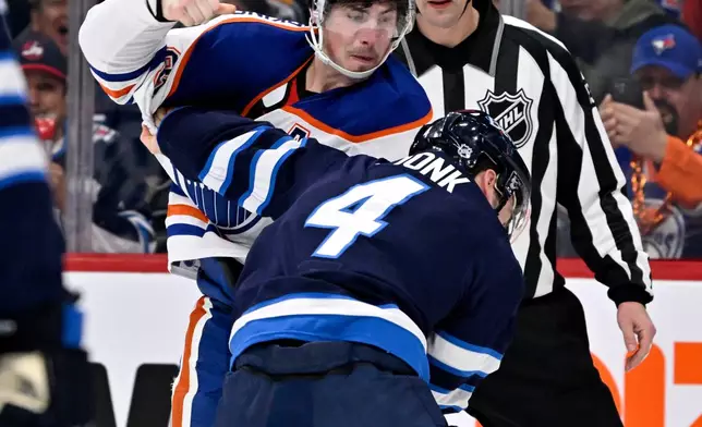 Edmonton Oilers' Ryan Nugent-Hopkins (93) fights with Winnipeg Jets' Neal Pionk (4) during the first period of an NHL hockey game in Winnipeg, Manitoba, Monday, Dec. 29, 2025. (Fred Greenslade/The Canadian Press via AP)