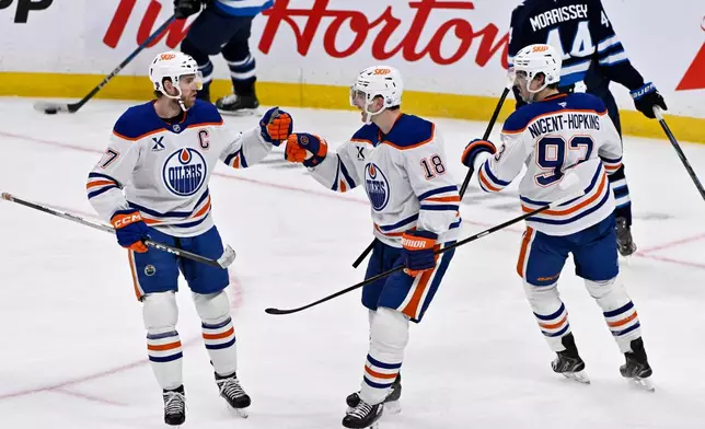 Edmonton Oilers' Zach Hyman (18) celebrates his empty net goal against the Winnipeg Jets with teammates Connor McDavid (97) and Ryan Nugent-Hopkins (93) during the third period of an NHL game in Winnipeg, Monday Dec. 29, 2025. (Fred Greenslade/The Canadian Press via AP)