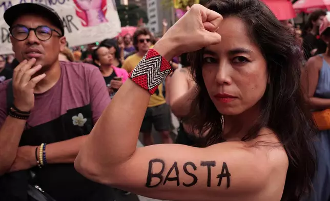 A demonstrator shows the word "Enough" written on her arm in Portuguese, during a march against femicide following a series of high-profile cases in the country, in Sao Paulo, Sunday, Dec. 7, 2025. (AP Photo/Ettore Chiereguini)