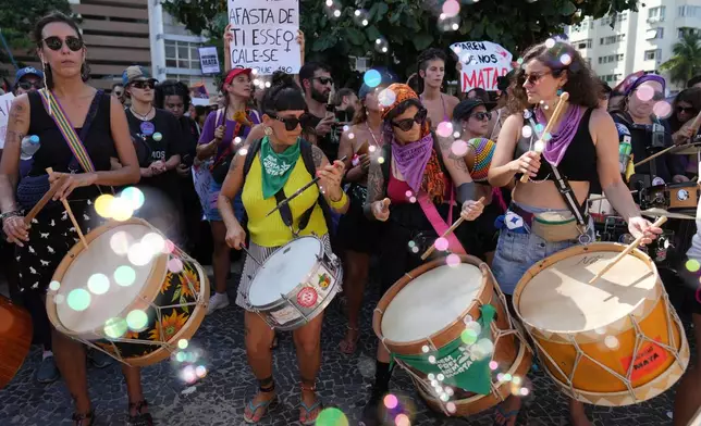 Women protest femicide following a series of high-profile cases in the country, on Copacabana beach, Rio de Janeiro, Sunday, Dec. 7, 2025. (AP Photo/Silvia Izquierdo)